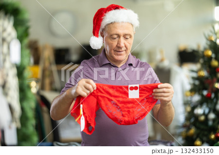 Positive mature man choosing red panties in clothing store Positive mature man choosing red panties in clothing store 132433150