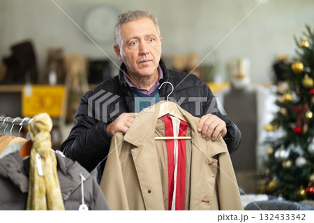 Attentive mature man choosing jacket in clothing store Attentive mature man choosing jacket in clothing store 132433342