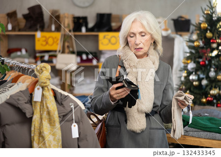 mature woman chooses gloves against the background of a Christmas tree 132433345