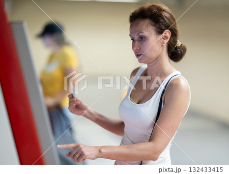 Adult woman using ticket machine at station 132433415