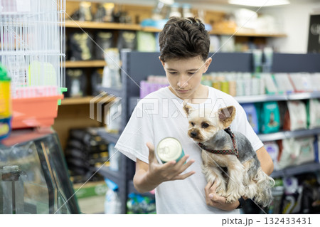 Focused preteen boy choosing canned dog food for Yorkie in pet store 132433431