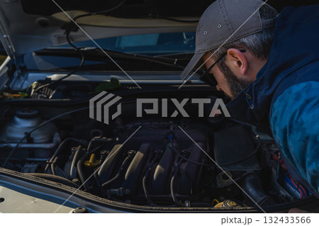 Car engine inspection by a man with glasses and a cap Car engine inspection by a man with glasses and a cap 132433566