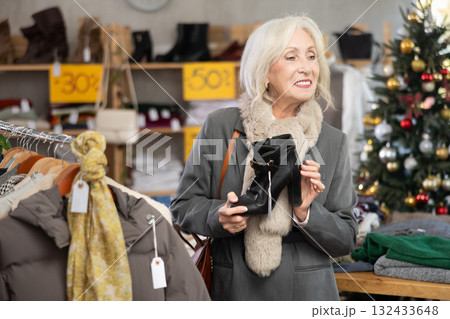 Mature woman choosing heeled boots in Christmas shop Mature woman choosing heeled boots in Christmas shop 132433648