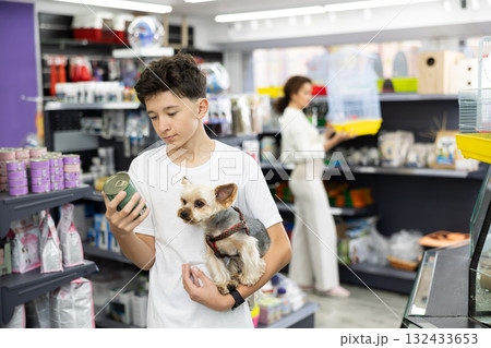 Teenage boy choosing canned dog food for Yorkshire terrier at pet store Teenage boy choosing canned dog food for Yorkshire terrier at pet store 132433653