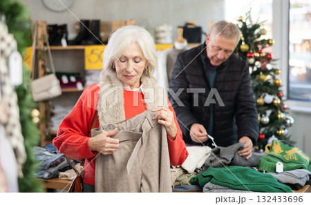 Attentive mature woman choosing pantaloons in clothing store Attentive mature woman choosing pantaloons in clothing store 132433696