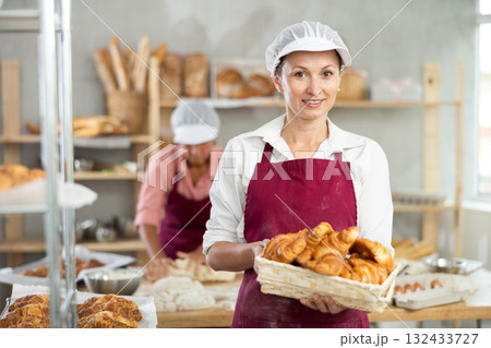 Adult woman baker with basket of croissants 132433727
