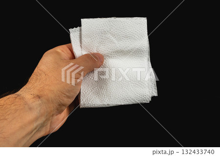 Hand holding clean paper towels against plain black background Hand holding clean paper towels against plain black background 132433740