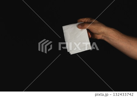 Hand holding a stack of white napkins in low light setting 132433742