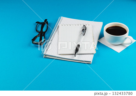 Coffee break with notebook and glasses on a bright blue background 132433780
