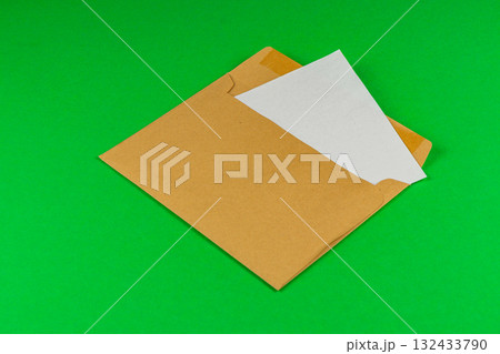 Brown envelope with blank paper on vibrant green background Brown envelope with blank paper on vibrant green background 132433790
