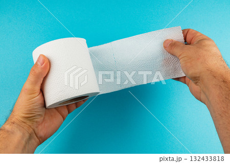Person holding a roll of white paper towel against a blue background 132433818