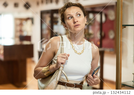 Woman curiously observing antique artifacts in historical museum 132434112