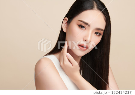 A beautiful young Asian woman with clean, fresh skin against a beige background. Skincare, facial treatment, cosmetology, beauty, and spa. An elegant portrait of an Asian woman. 132434237