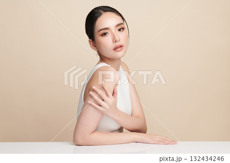 A beautiful young Asian woman with clean, fresh skin against a beige background. Skincare, facial treatment, cosmetology, beauty, and spa. An elegant portrait of an Asian woman. A beautiful young Asian woman with clean, fresh skin against a beige background. Skincare, facial treatment, cosmetology, beauty, and spa. An elegant portrait of an Asian woman. 132434246