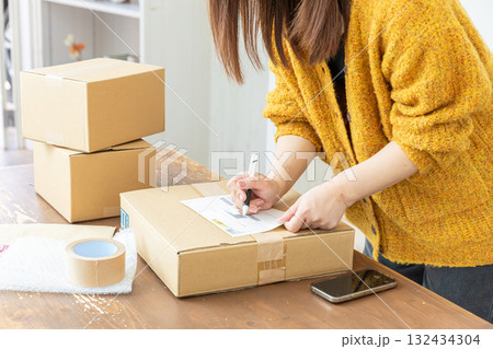 荷造りする女性の手元 132434304