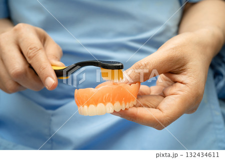 Asian senior woman patient clean teeth denture with toothbrush for chew food. Asian senior woman patient clean teeth denture with toothbrush for chew food. 132434611
