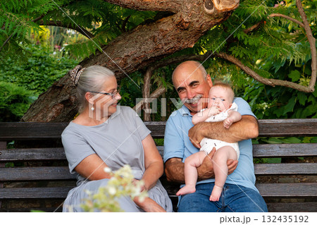 Senior couple enjoying moment with baby in green garden 132435192