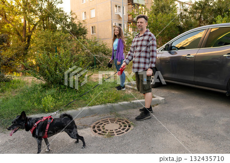 Father and daughter walking dog with leash near parked car Father and daughter walking dog with leash near parked car 132435710
