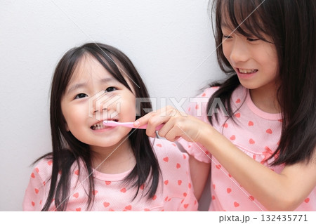 パジャマで歯磨きをする4歳と10歳の姉妹の女の子 パジャマで歯磨きをする4歳と10歳の姉妹の女の子 132435771