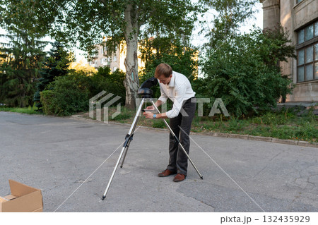 Man checks telescope tripod mount during setup process 132435929