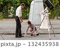 Instructor shows astronomy student telescope mount component outdoors 132435938