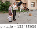 Astronomy lesson with telescope setup outside educational building 132435939