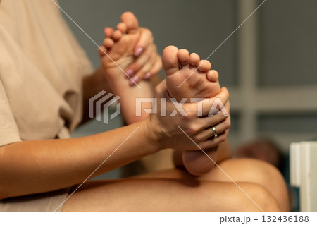 Mother gently massaging child's bare feet indoors Mother gently massaging child's bare feet indoors 132436188