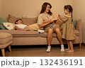 Mother and daughter interact while son plays on sofa 132436191