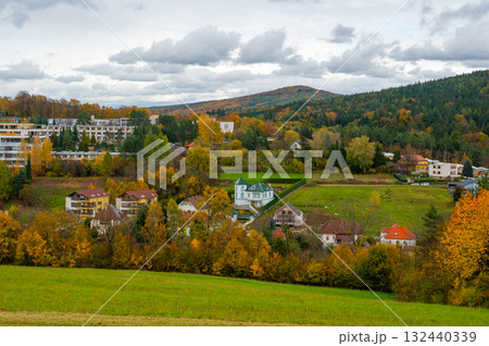 Panoramic view of the hills around Luhacovice, Czech Republic, with small houses scattered on the slopes surrounded by colorful autumn trees in red, orange, and yellow tones. 132440339