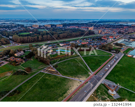 Aerial view of coastal urban park sandy beach, promenade, triangular pavilion, circular playgrounds, and dense residential blocks near river blend recreation, architecture, and shoreline planning. Aerial view of coastal urban park sandy beach, promenade, triangular pavilion, circular playgrounds, and dense residential blocks near river blend recreation, architecture, and shoreline planning. 132441994