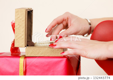 Female hands opening golden gift box with jewel pearls 132443774