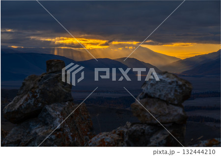 Golden sunset over a mountain valley with rocky foreground and dramatic light rays Golden sunset over a mountain valley with rocky foreground and dramatic light rays 132444210