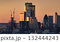 Bright orange sunset light over modern glass skyscrapers in London's financial district, iconic buildings like the Gherkin and active construction cranes. Business center skyline. Drone flight Bright orange sunset light over modern glass skyscrapers in London's financial district, iconic buildings like the Gherkin and active construction cranes. Business center skyline. Drone flight 132444243
