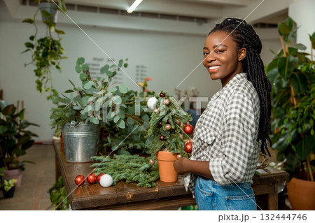 Long-haired african american woman looking contented while working in a flower shop Long-haired african american woman looking contented while working in a flower shop 132444746