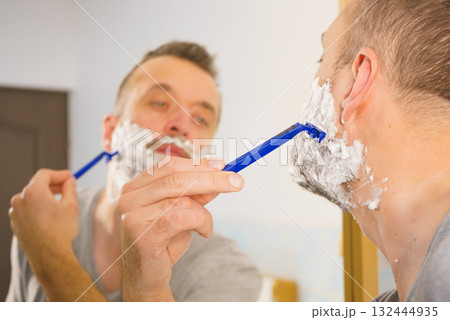 Guy shaving his beard in bathroom 132444935
