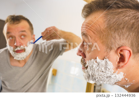 Guy shaving his beard in bathroom 132444936