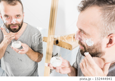 Man applying moisturizer cream in bathroom Man applying moisturizer cream in bathroom 132444941