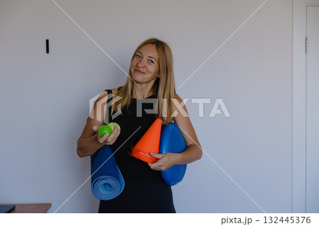 fit professional getting ready for class, active instructor in bright room preparing fitness session fit professional getting ready for class, active instructor in bright room preparing fitness session 132445376
