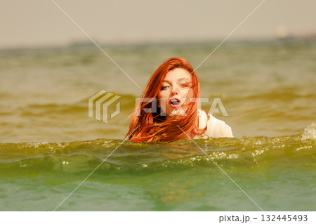 Redhead woman playing in water during summertime 132445493