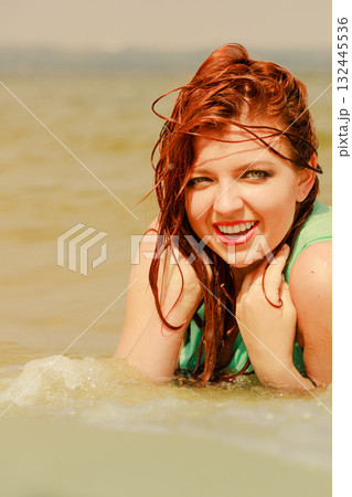 Redhead woman posing in water during summertime Redhead woman posing in water during summertime 132445536