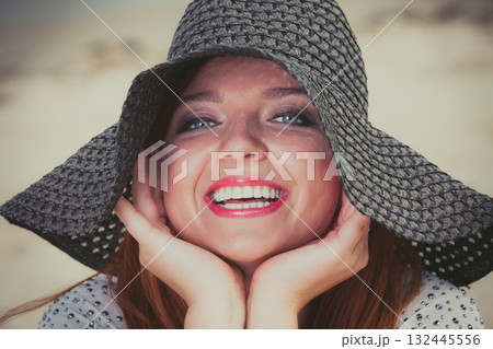 Happy redhead woman wearing big black sun hat 132445556