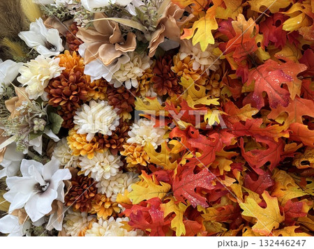 A vibrant mix of artificial autumn flowers and colorful leaves in warm tones A vibrant mix of artificial autumn flowers and colorful leaves in warm tones 132446247