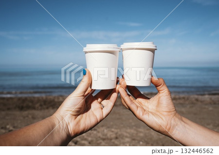 Holding Coffee Cups at the Beach on a Sunny Day 132446562