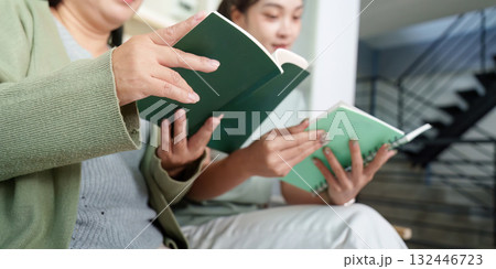 Mother and daughter reading books together in cozy setting 132446723