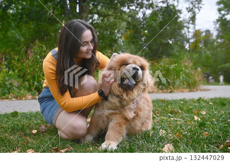 Young woman and her dog are relaxing in a park. Young adult woman with a Chow Chow outdoor Young woman and her dog are relaxing in a park. Young adult woman with a Chow Chow outdoor 132447029