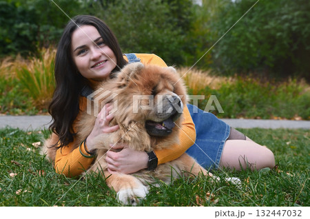 Young woman and her dog are relaxing in a park. Young adult woman with a Chow Chow outdoor Young woman and her dog are relaxing in a park. Young adult woman with a Chow Chow outdoor 132447032
