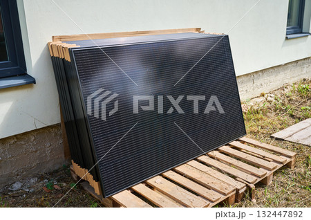 Stack of new solar panels with protective cardboard, ready for installation. Renewable energy, sustainable home improvements, and eco-friendly investments in residential property infrastructure. Stack of new solar panels with protective cardboard, ready for installation. Renewable energy, sustainable home improvements, and eco-friendly investments in residential property infrastructure. 132447892