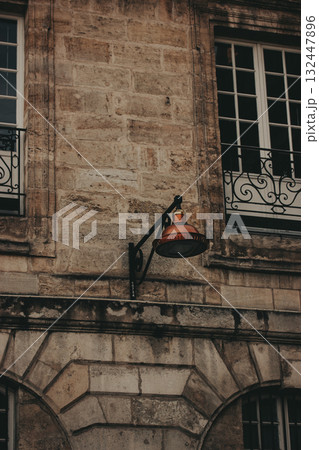Old building facade with a vintage street lamp. An aged building exterior with a decorative ironwork, a classic copper street lamp. European street Old building facade with a vintage street lamp. An aged building exterior with a decorative ironwork, a classic copper street lamp. European street 132447896