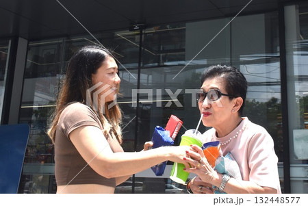 mother and daughter buy cold drink and snack and walking in front of convenience store 132448577