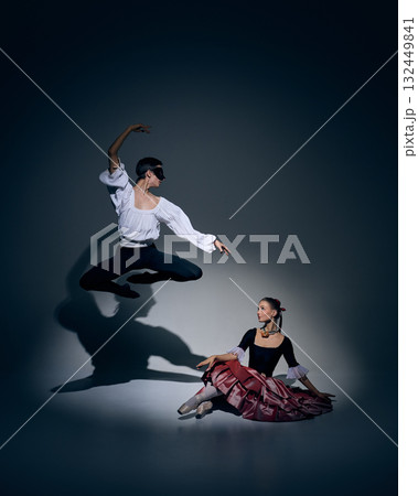 Leap of trust. Ballet dancer in mid-air above partner under focused light. 132449841